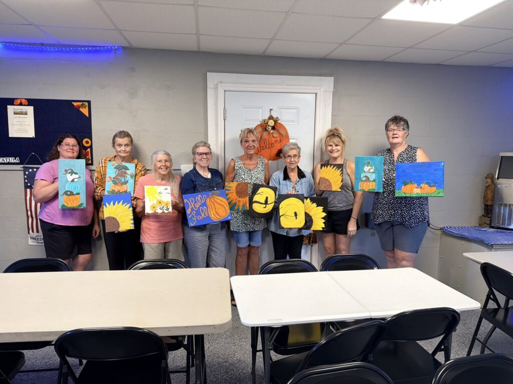 Hide-A-Way Harbor community members displaying their paintings indoors