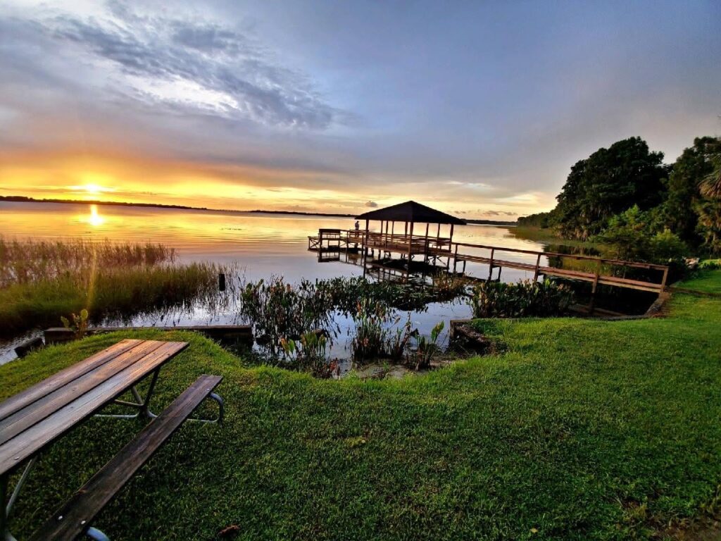 Covered lakefront dock and picnic table at sunset at Hide-A-Way Harbor